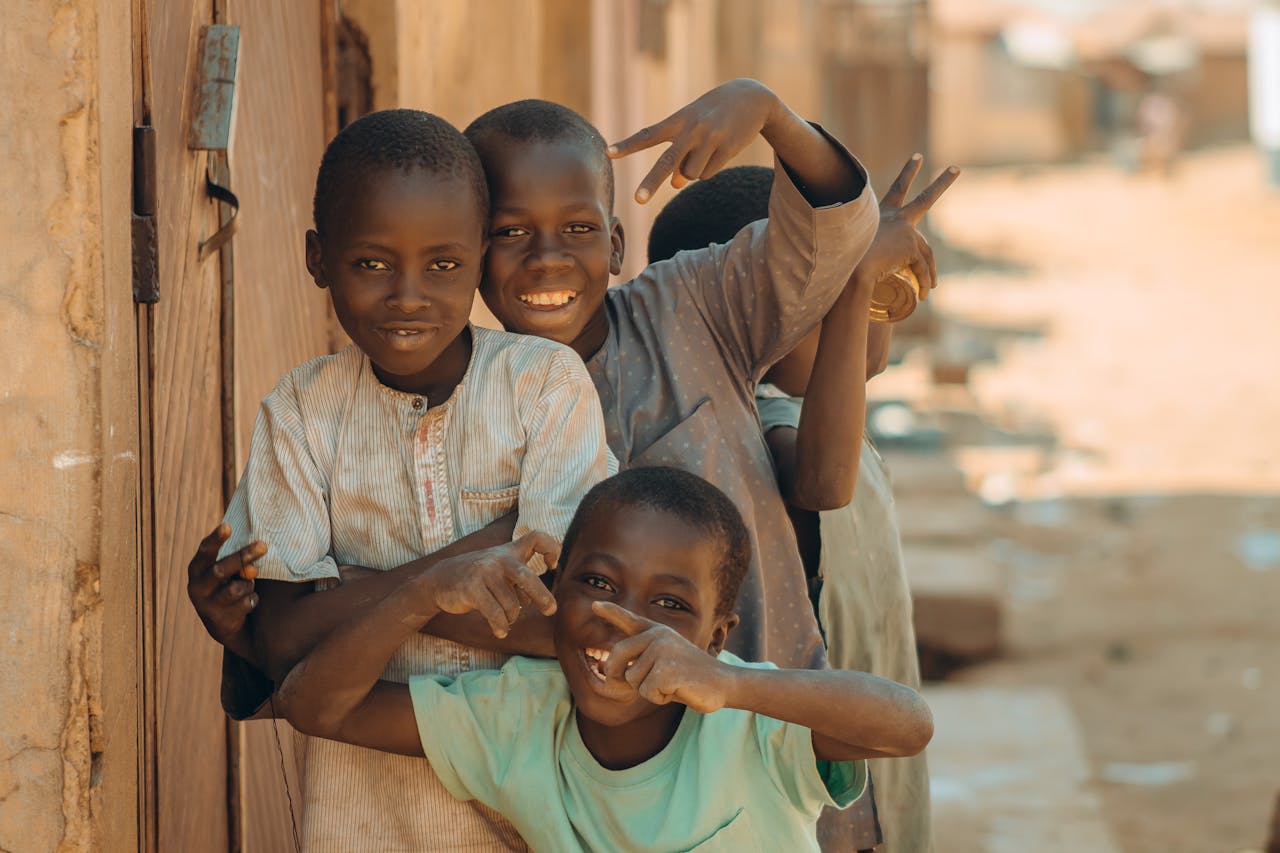 Four cheerful children pose and play on a sunny day in an African neighborhood.